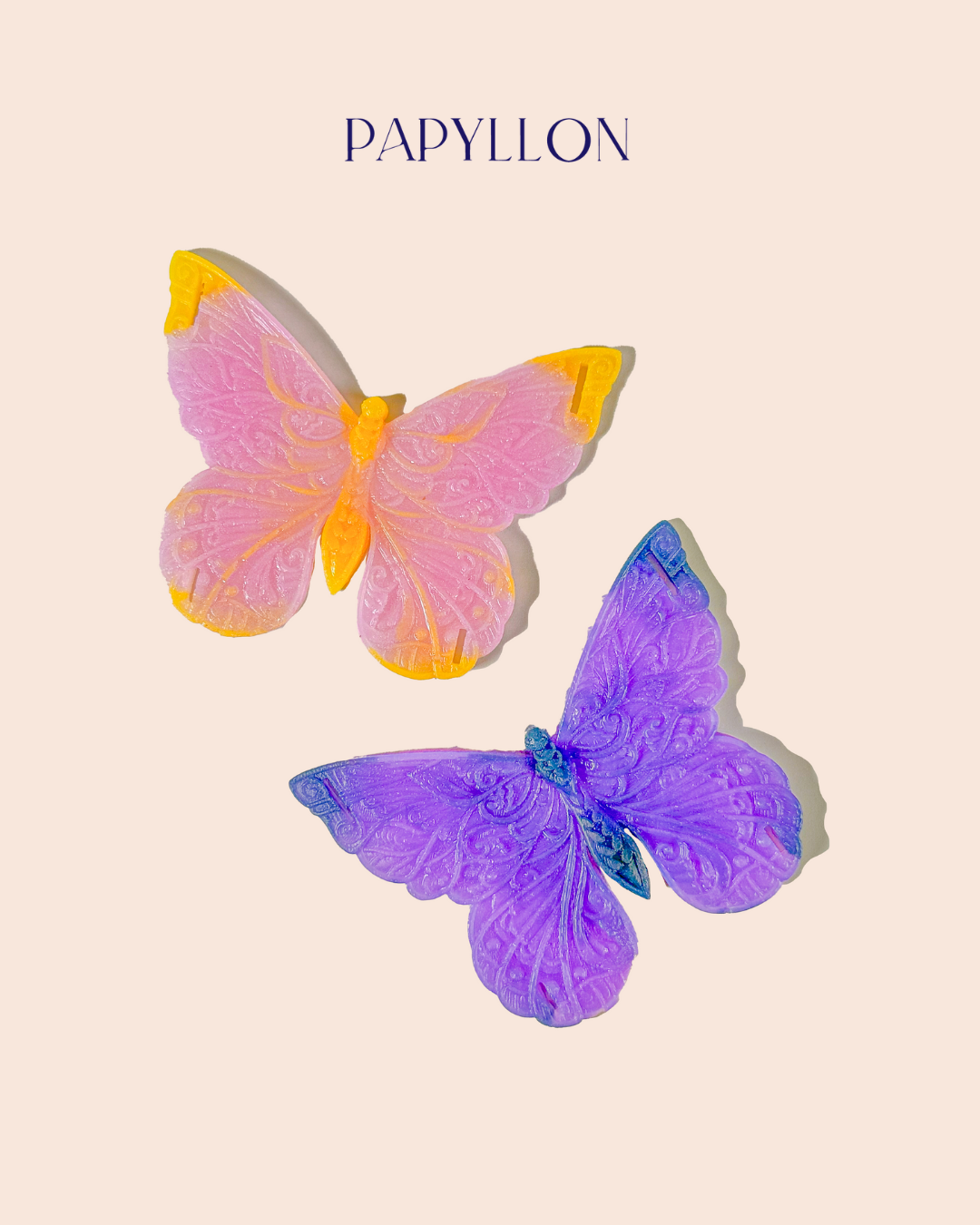 Two colorful butterfly-shaped intimate objects on a beige background with 'PAPYLLON' branding.