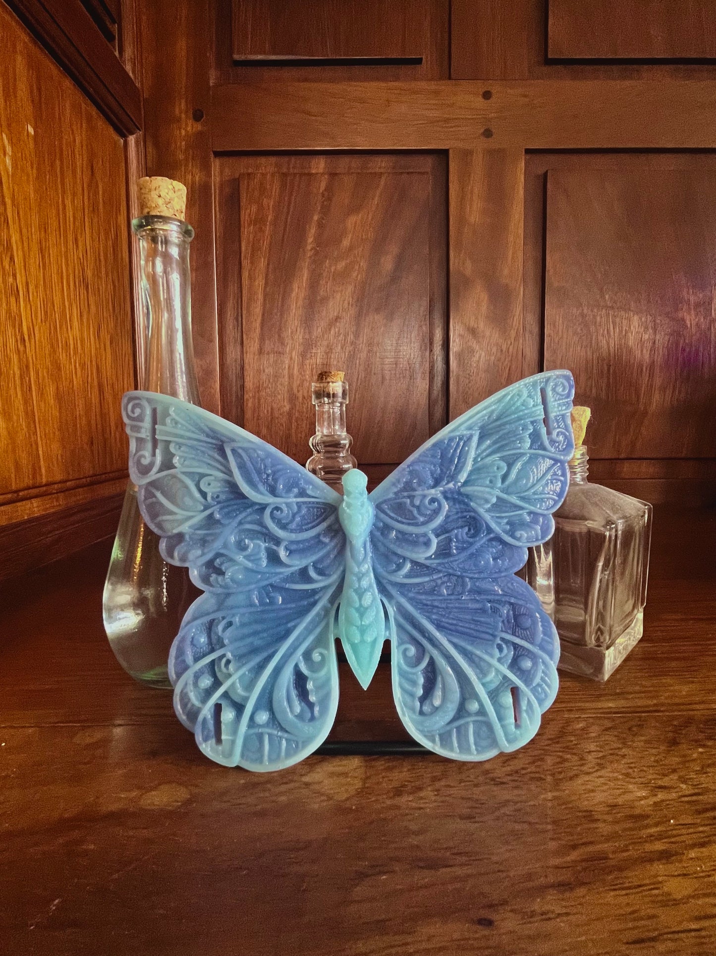 Papyllon modèle ailes et corps de la marque Playsir. vue de face. Ce papillon aux deux bleus est posé dans un bibliothèque en bois avec d'autres décorations d'intérieur