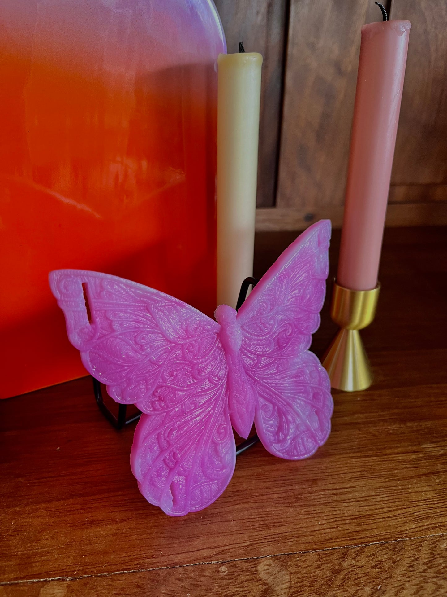 Papyllon, objet intime en forme de papillon de la marque Playsir. Ce jouet érotique est posé sur la bibliothèque avec un vase et des bougies et autres objets de décoration. Entièrement fabriqué en silicone body-safe pour un usage intime.