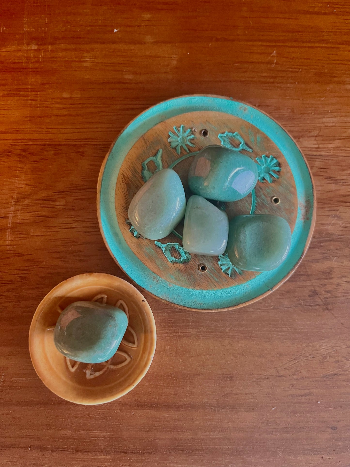Pierre demi précieuse aventurine polie. inclus dans les bougies Krystal de la marque Playsir dans le collection Découverte et curiosité. Pierres naturelles vertes, posé dans une petite coupelle en terre cuite et une autre en bois peint sur une surface en bois massif. Vue de dessus