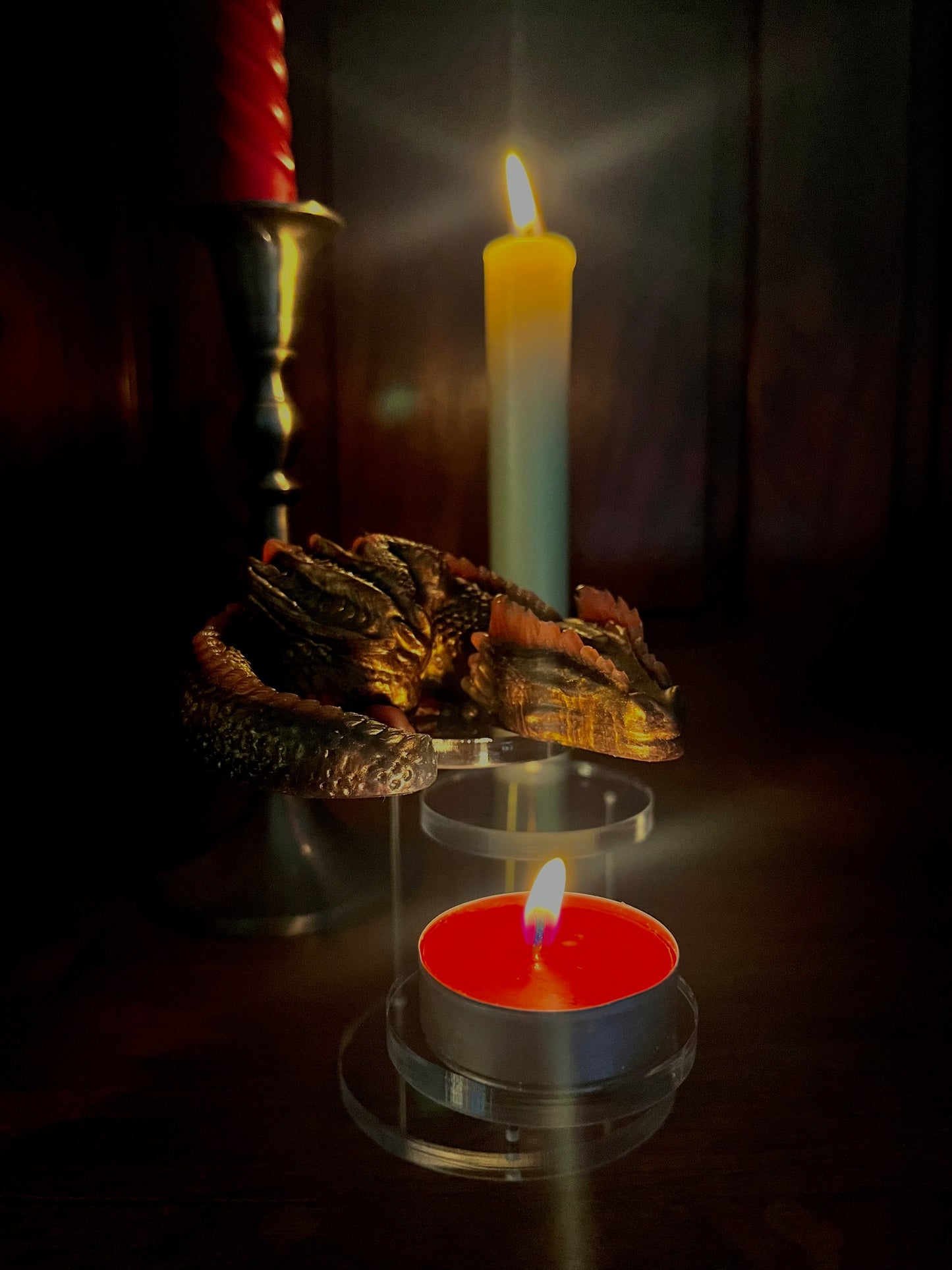 Jouet anti-stress Dragon en silicone, couleurs bronze et rouge. Mis en scène sur un présentoir dans une lumière tamisé éclairé par deux bougies pour créer une ambiance intimiste.