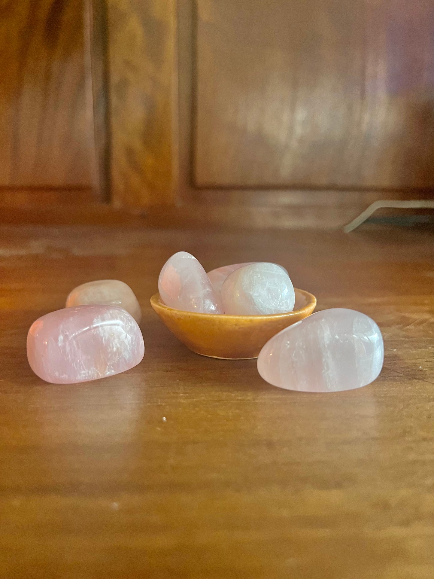 Pierres semi précieuses Quartz Rose, inclus dans les bougies Krystal de la arque Playsir dans le collection Lien du cœur. Pierres naturelles roses, posé dans une petite coupelle su rune surface en bois massif. Vue de face