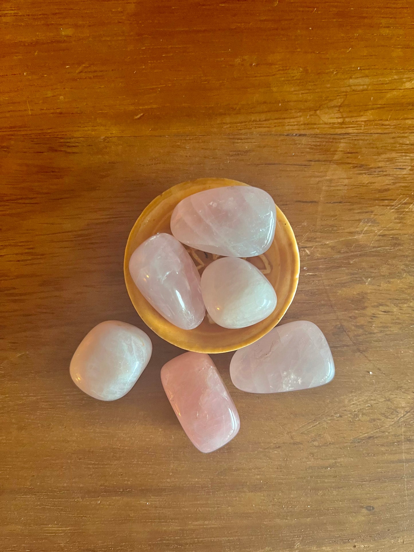 Pierres semi précieuses Quartz Rose, inclus dans les bougies Krystal de la arque Playsir dans le collection Lien du cœur. Pierres naturelles roses, posé dans une petite coupelle su rune surface en bois massif.  Vue de dessus