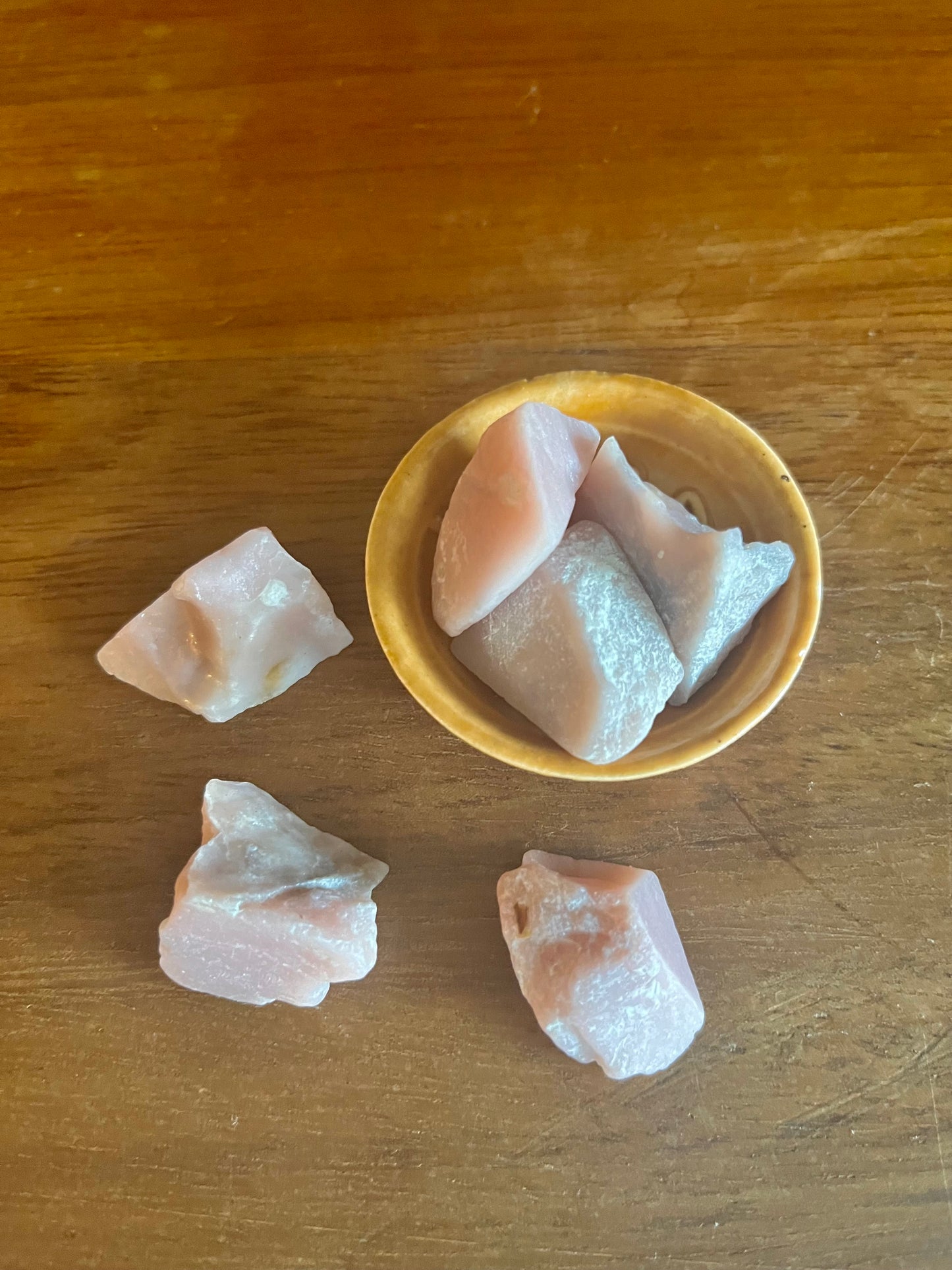 Pierre demi précieuse Opal Rose brute. inclus dans les bougies Krystal de la marque Playsir dans le collection Lien du cœur. Pierres naturelles texturés roses, posé dans une petite coupelle sur une surface en bois massif. Vue de dessus