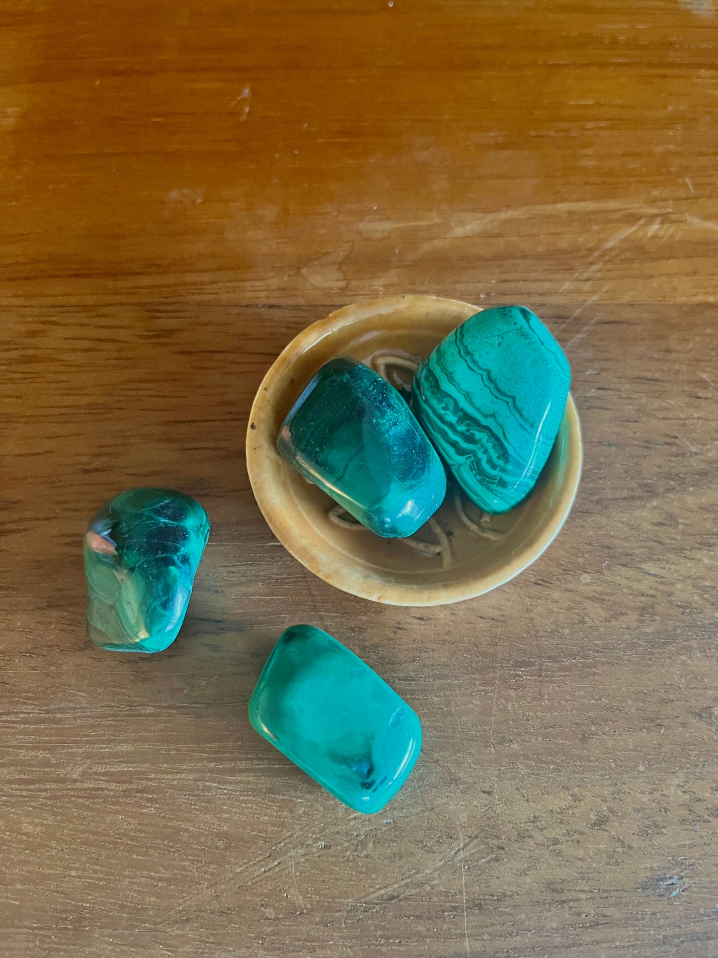 Pierres semi précieuses malachite, inclus dans les bougies Krystal de la marque Playsir dans le collection Lien du cœur. Pierres naturelles avec veines vertes , posé dans une petite coupelle sur une surface en bois massif. Vue de dessus