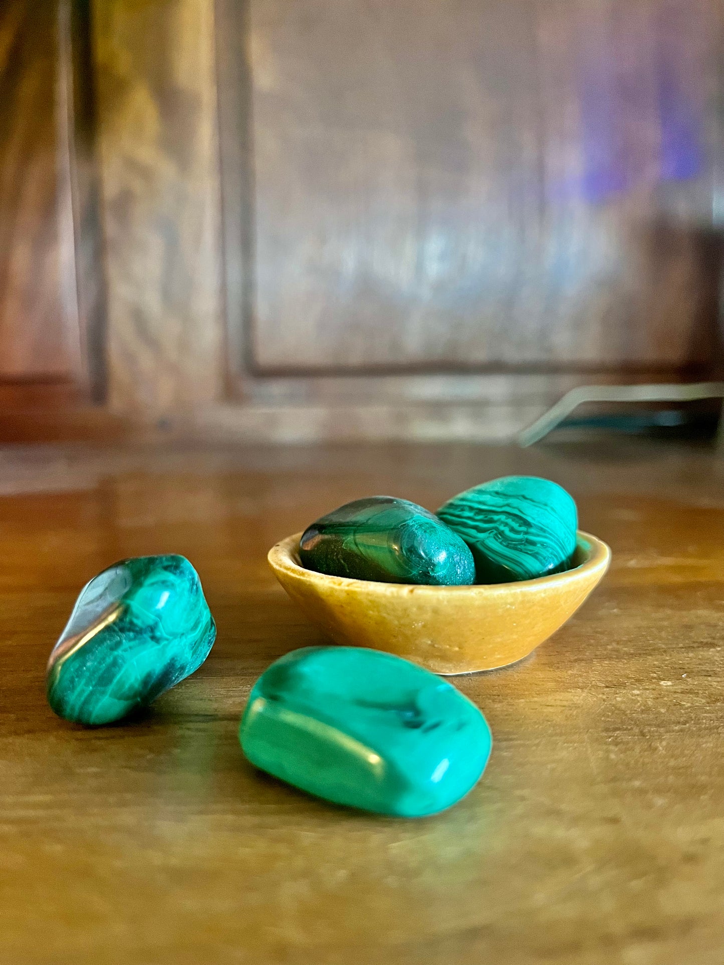 Pierres semi précieuses malachite, inclus dans les bougies Krystal de la marque Playsir dans le collection Lien du cœur. Pierres naturelles avec veines vertes , posé dans une petite coupelle sur une surface en bois massif. 
