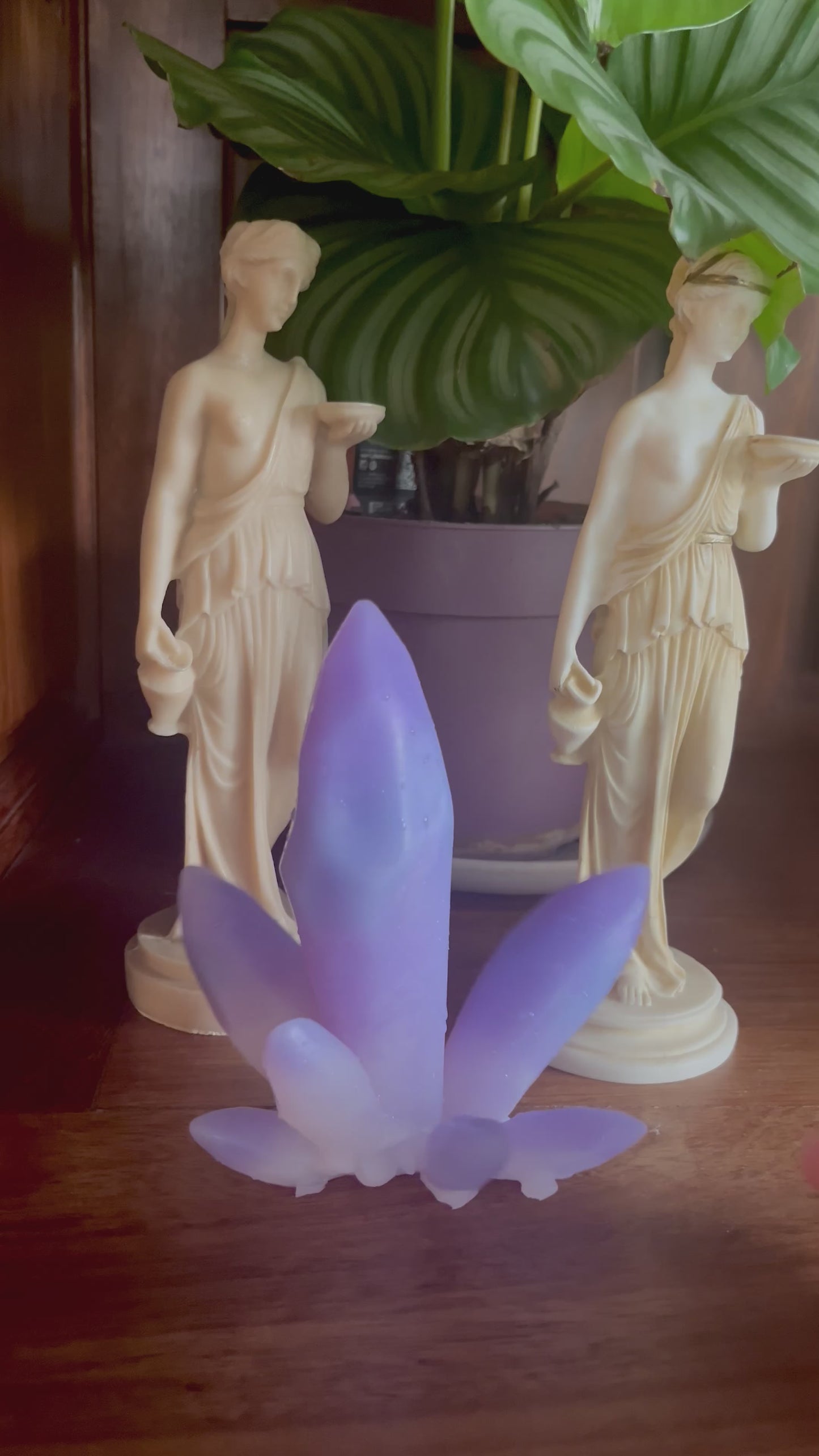 Objets Krystal, aux inspiration et apparence d'une pierre précieuse Améthyste. Objet intime et érotique en silicone violet devant un décor de statues grecques et une plate en pot. Vidéo qui monter la texture et l'élasticité du produit.